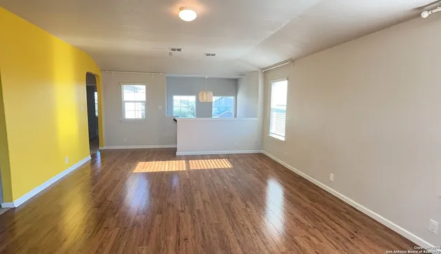 an empty room with wooden floor and windows