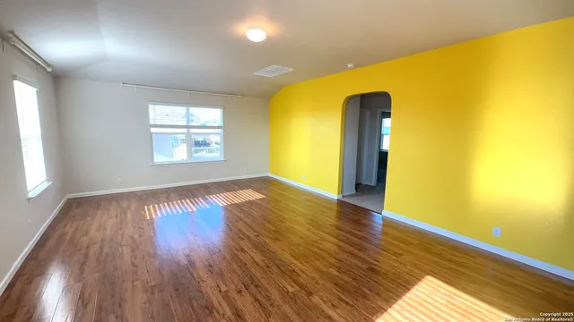a view of empty room with wooden floor and fan