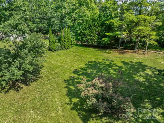 an aerial view of residential house with outdoor space and trees all around