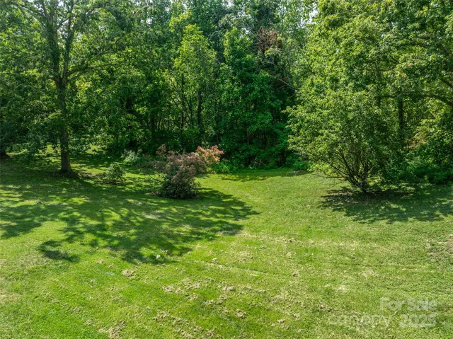 a view of a field with trees in front of the house