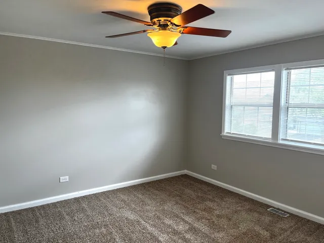 an empty room with windows and chandelier fan