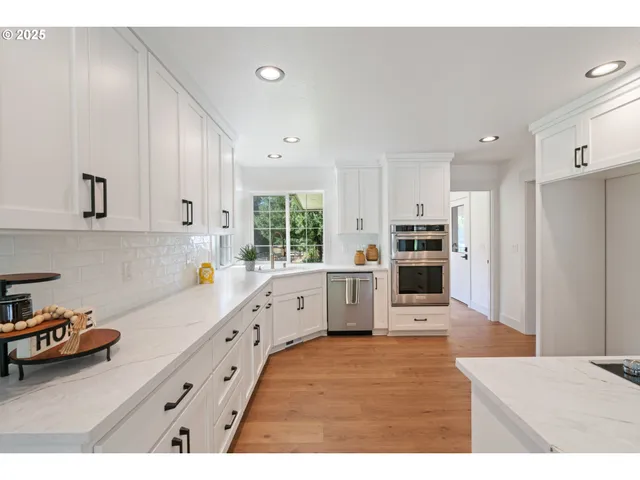 a kitchen that has a lot of cabinets a sink and appliances