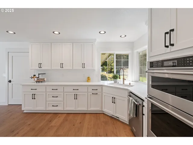 a kitchen with granite countertop white cabinets and stainless steel appliances