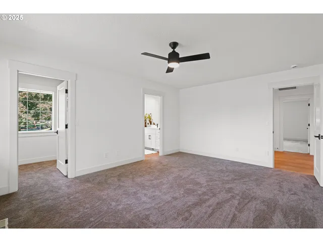 a view of empty room with wooden floor and ceiling fan