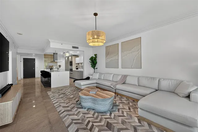 a living room with furniture kitchen view and a chandelier