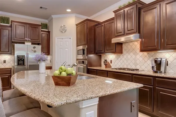 a kitchen with kitchen island granite countertop wooden cabinets a refrigerator and a sink