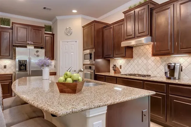 a kitchen with kitchen island granite countertop wooden cabinets a refrigerator and a sink