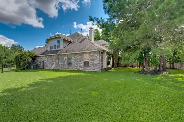 a view of a house with a big yard potted plants and large tree
