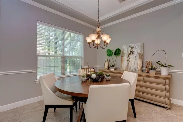 a view of a dining room with furniture a chandelier and large windows