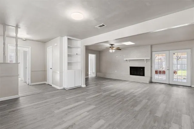 an empty room with wooden floor fireplace and windows