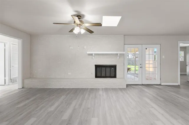 an empty room with wooden floor fireplace and windows