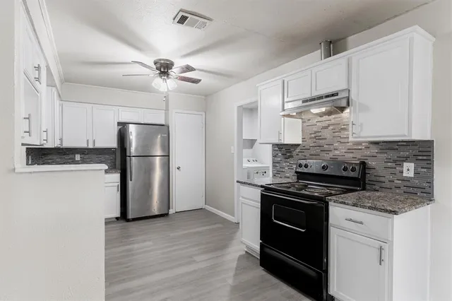a kitchen with stainless steel appliances granite countertop a refrigerator and a stove top oven