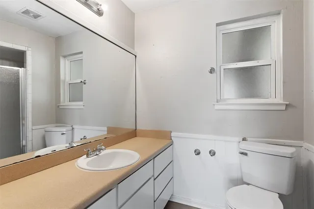 a bathroom with a granite countertop toilet sink and mirror