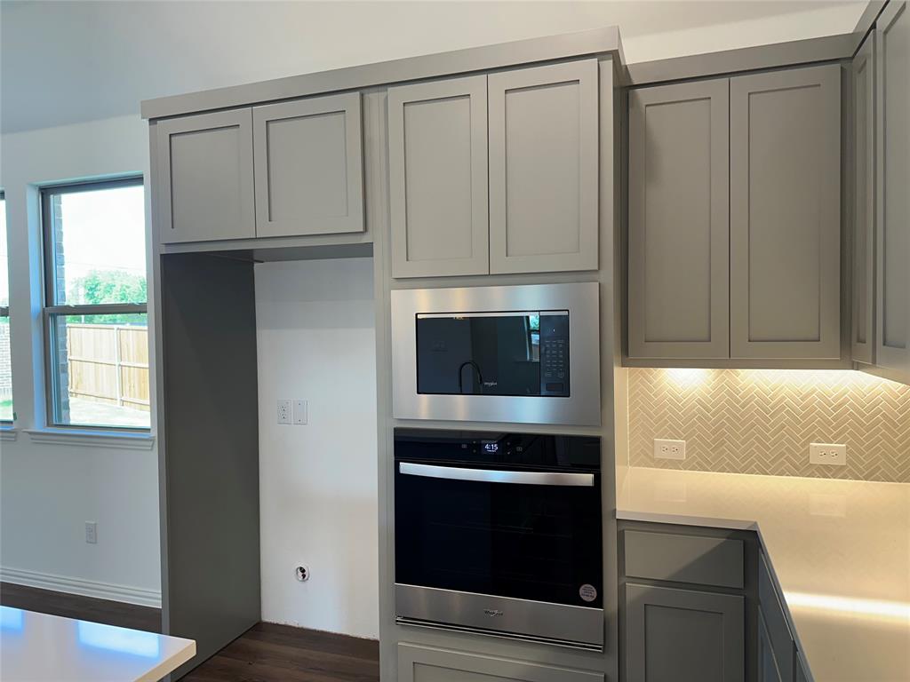 3401 Paintbrush Path Melissa, TX 75454 - Photo 23 of 39 Kitchen with gray cabinetry, stainless steel appliances, decorative backsplash, dark wood finished floors, and light stone counters