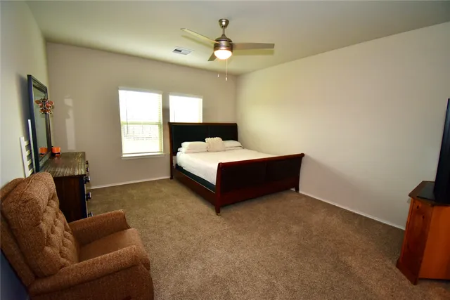 a spacious bedroom with a bed couch and window