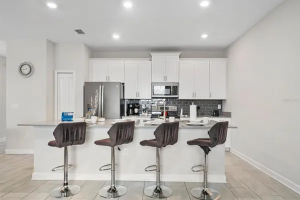 a kitchen with stainless steel appliances kitchen island granite countertop a refrigerator a stove a dining table and chairs with wooden floor