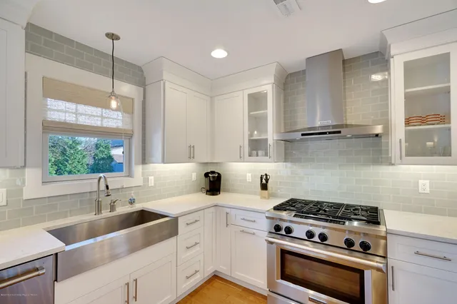 a kitchen with stainless steel appliances a sink a stove and white cabinets next to a window