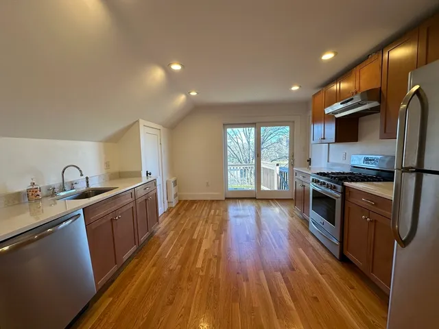 a kitchen with stainless steel appliances granite countertop wooden floors a stove and a sink