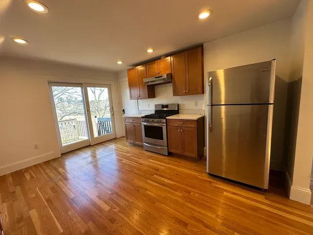 a kitchen with stainless steel appliances a refrigerator and wooden floor
