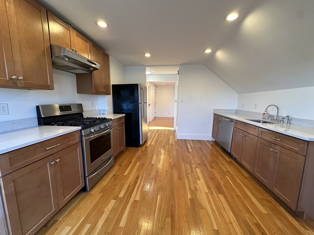 76 Wenham Street, Unit 3 Boston, MA 02130 - Photo 9 of 23 a kitchen with wooden floors and stainless steel appliances