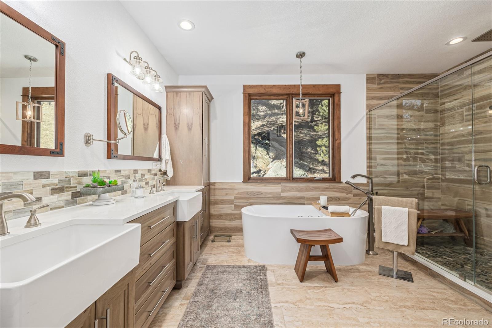 663 Brookside Drive Bailey, CO 80421 - Photo 16 of 47 a bathroom with a sink a bathtub a mirror a vanity a window and a shower