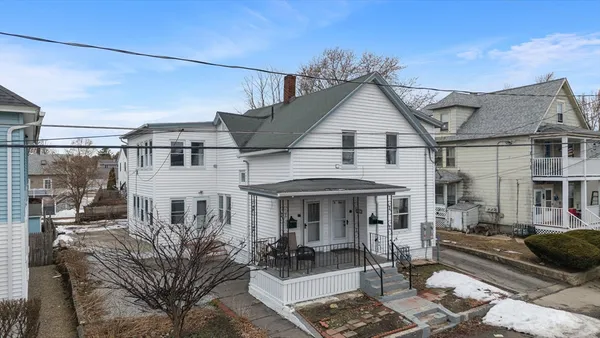 a view of a white house next to a yard
