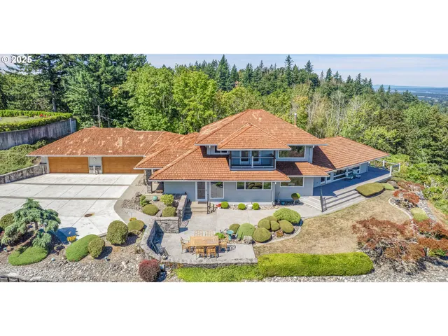 a view of a white house with a yard and table and chairs under an umbrella
