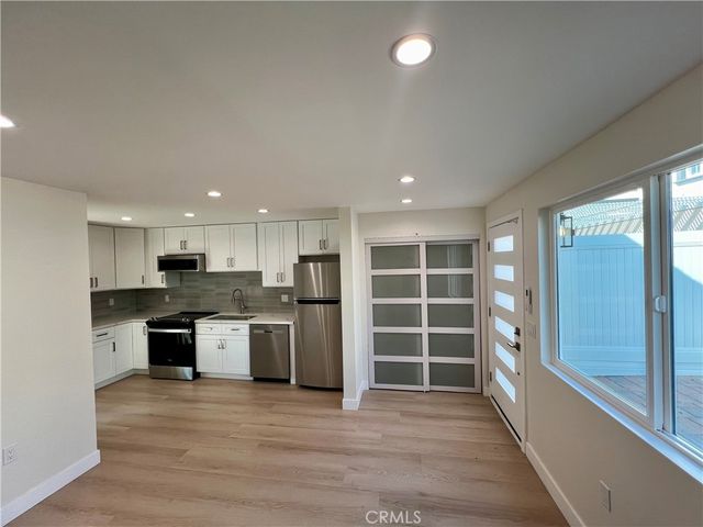 a view of kitchen with kitchen island wooden floor center island and stainless steel appliances