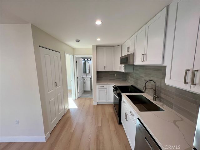 a kitchen with granite countertop a sink a refrigerator and cabinets