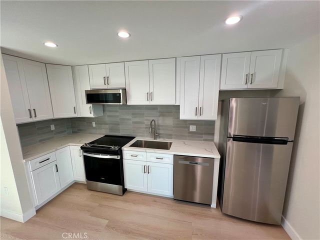a kitchen with a sink a refrigerator and white cabinets