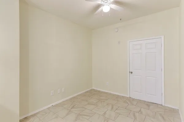 an empty room with a chandelier fan and windows