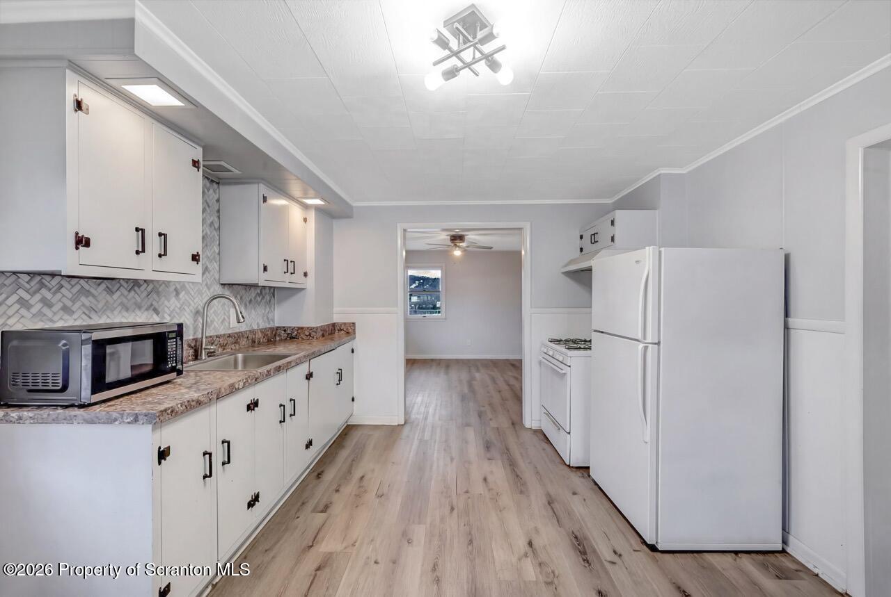 641 East Elm Street Scranton, PA 18505 - Photo 32 of 59 a kitchen with granite countertop a refrigerator a sink dishwasher and white cabinets with wooden floor