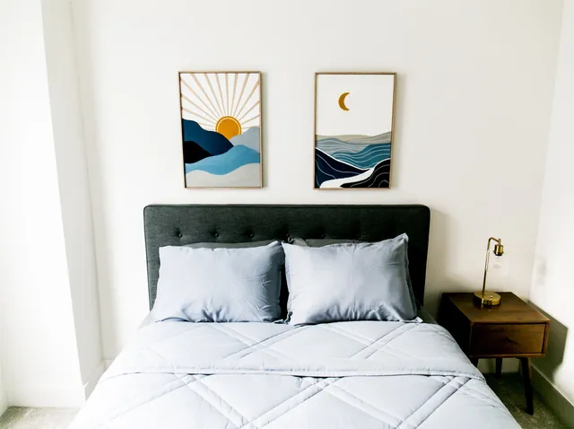 a bedroom with a bed and painting on the wall