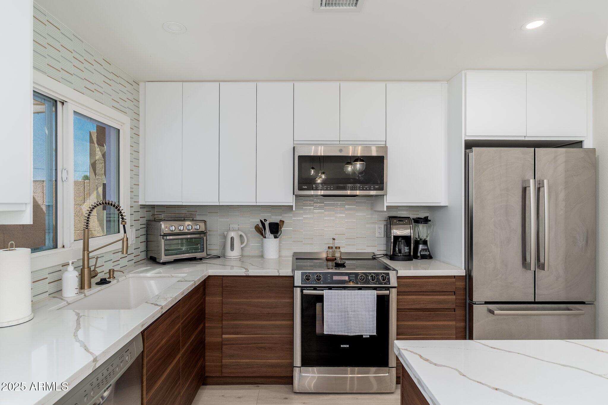 6957 East Osborn Road, Unit A Scottsdale, AZ 85251 - Photo 12 of 29 a kitchen with stainless steel appliances a refrigerator sink and cabinets
