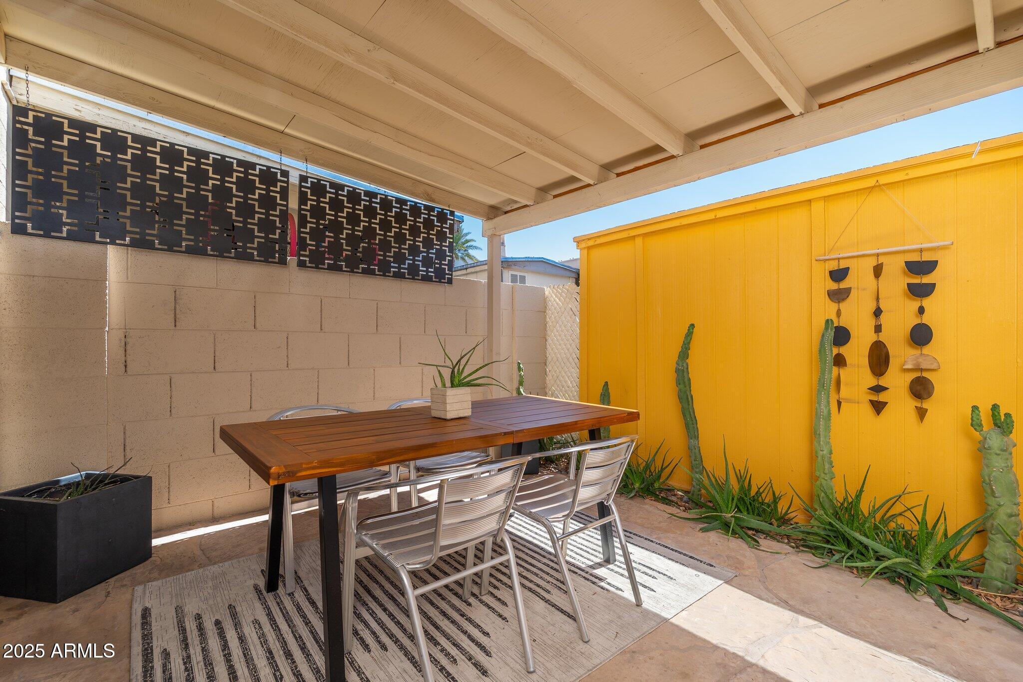 6957 East Osborn Road, Unit A Scottsdale, AZ 85251 - Photo 23 of 29 a view of a patio with table and chairs with wooden floor and plants