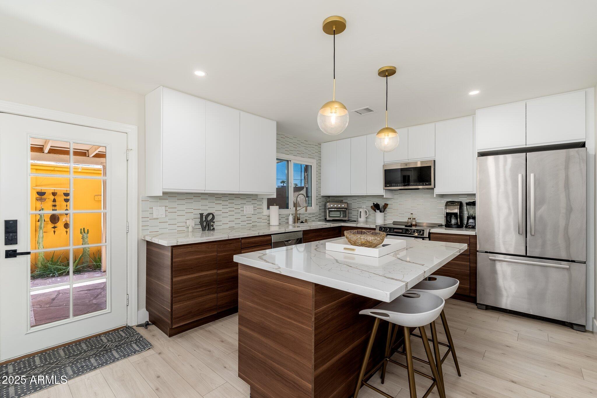 6957 East Osborn Road, Unit A Scottsdale, AZ 85251 - Photo 10 of 29 a kitchen with stainless steel appliances granite countertop a sink a stove a refrigerator and island with wooden floor