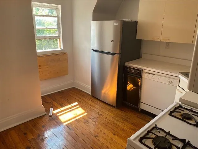 a kitchen with a refrigerator and wooden floor