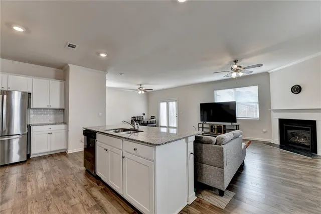 a open kitchen with stainless steel appliances a stove top oven a refrigerator a dining table and chairs with wooden floor