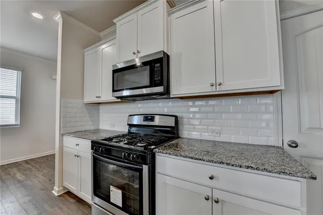 a kitchen with granite countertop stainless steel appliances a stove microwave and sink