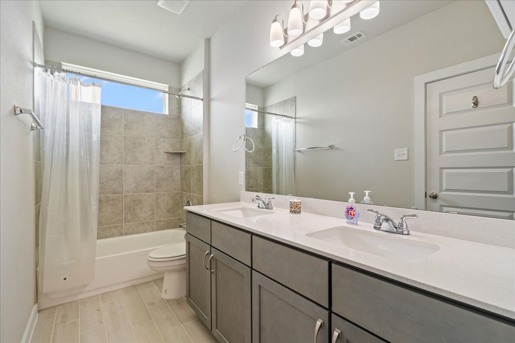 330 Hortus Drive Kyle, TX 78640 - Photo 15 of 26 a bathroom with a double vanity sink mirror double shower and a bathtub