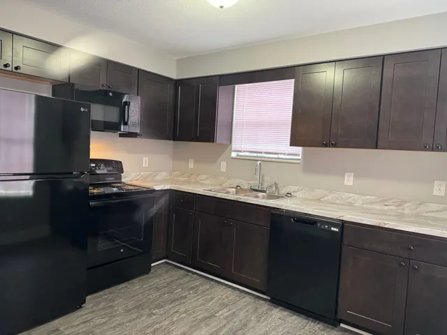a kitchen with granite countertop a sink stainless steel appliances and cabinets