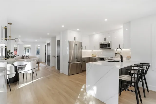 a kitchen with a dining table chairs wooden floor appliances and cabinets