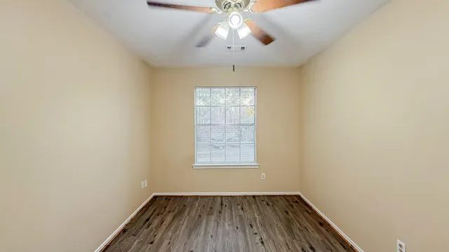 an empty room with a window and wooden floor