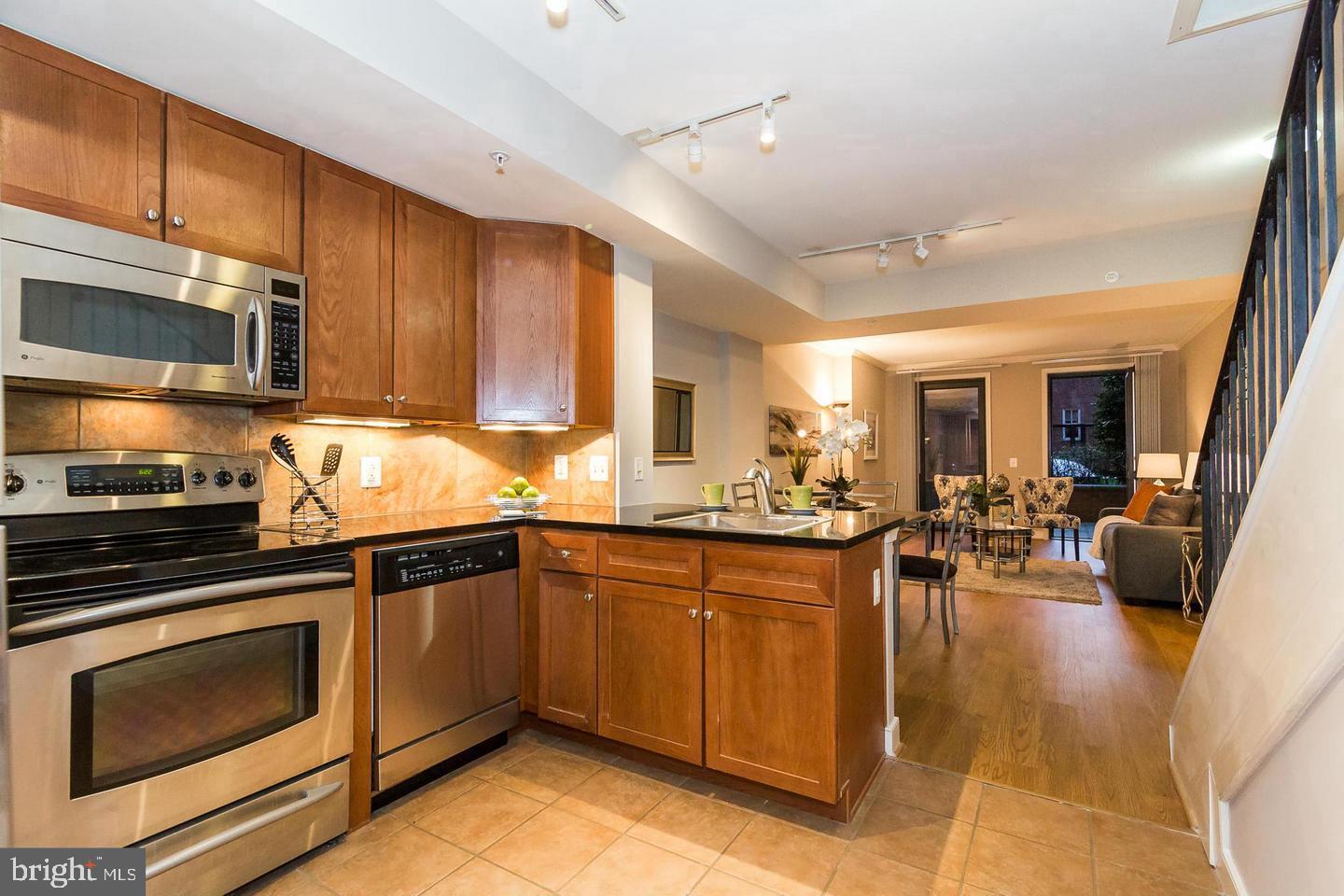 616 E Street Northwest, Unit 246 Washington, DC 20004 - Photo 5 of 40 a kitchen with stainless steel appliances stove microwave refrigerator dining table and chairs