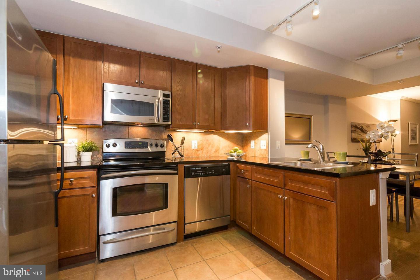 616 E Street Northwest, Unit 246 Washington, DC 20004 - Photo 7 of 40 a kitchen with granite countertop wooden cabinets stainless steel appliances and a counter space