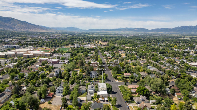 299 West Center Street, Unit 2 Logan, UT 84321 - Photo 42 of 46 Aerial perspective showcasing a residential and commercial area with abundant mature trees, mountain ranges in the distance, and prominent buildings