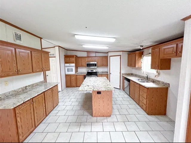 a large kitchen with stainless steel appliances granite countertop a stove top oven a sink dishwasher and cabinets