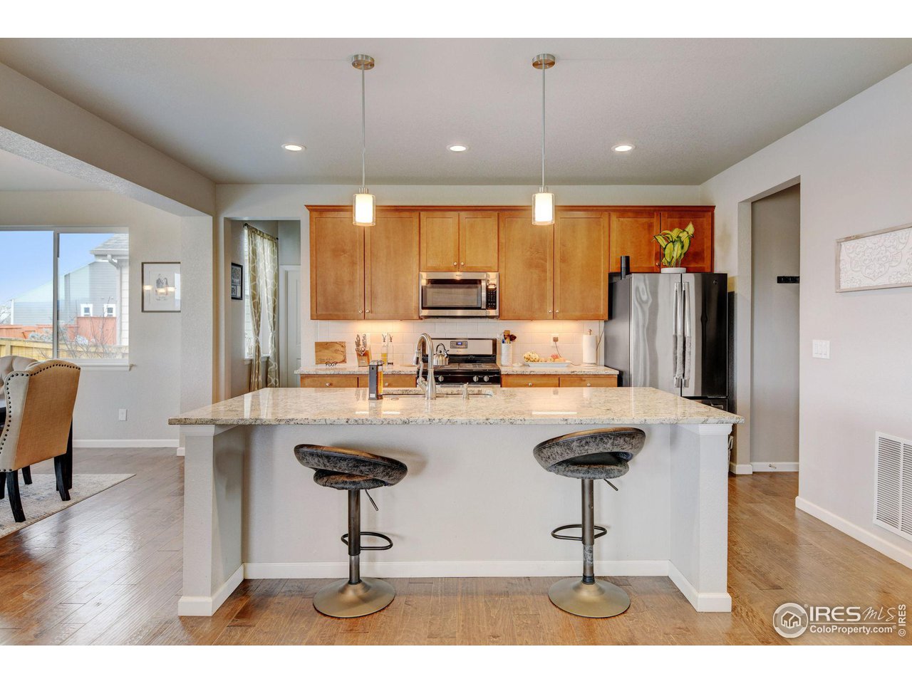 620 Wagon Bend Road Berthoud, CO 80513 - Photo 11 of 39 a kitchen with stainless steel appliances kitchen island granite countertop a refrigerator a stove a sink a dining table and chairs with wooden floor