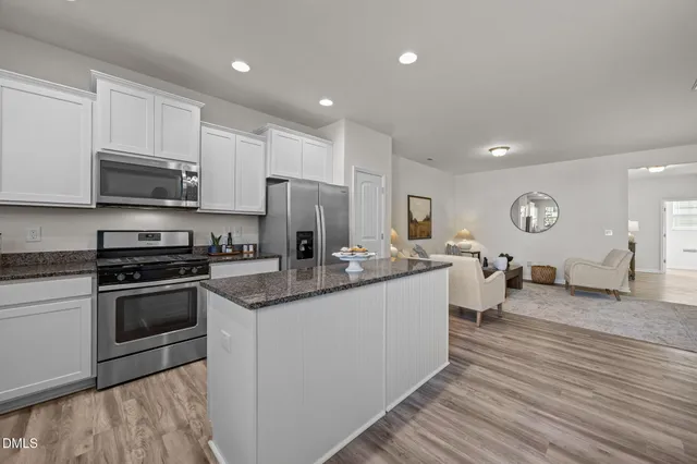 a large kitchen with stainless steel appliances granite countertop a stove a sink dishwasher and a refrigerator with wooden floor