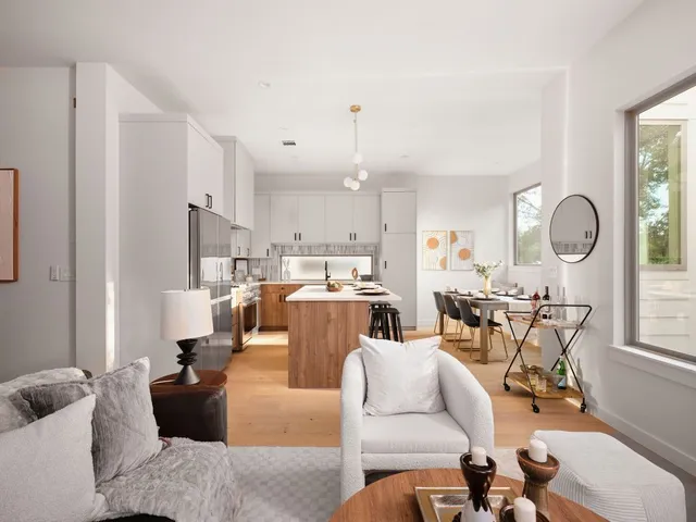 a living room with furniture kitchen view and a large window